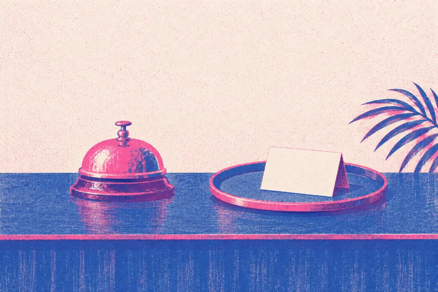 A pink desk bell beside a round tray with one folded card standing on it.